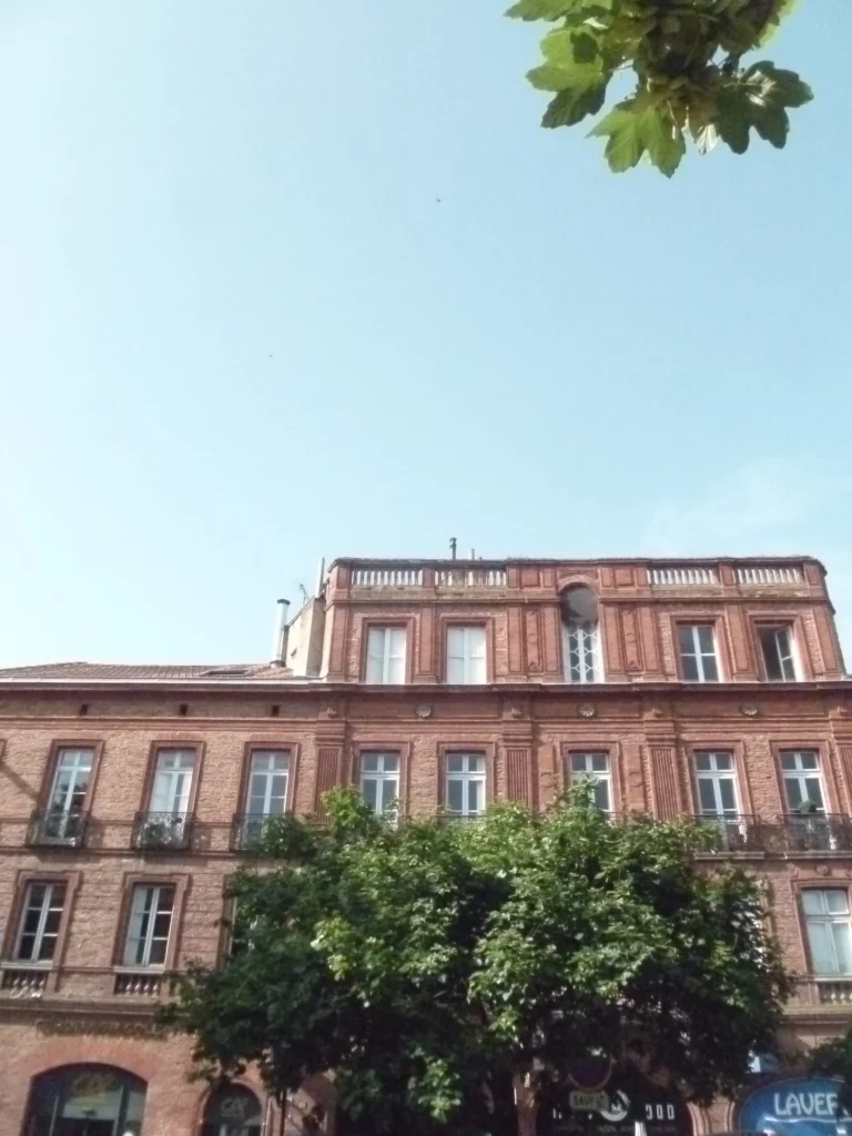 Façade en brique d’un immeuble toulousain sous un ciel bleu