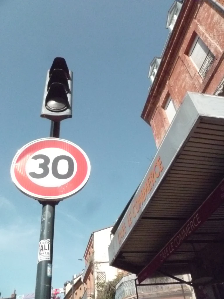 Un panneau de limitation à 30 vu en contre-plongée devant un immeuble en brique
