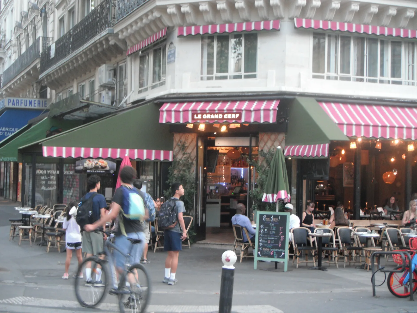 Terrasse de café parisienne aux stores rayés roses et verts en fin de journée, au Fujifilm FinePix XP15