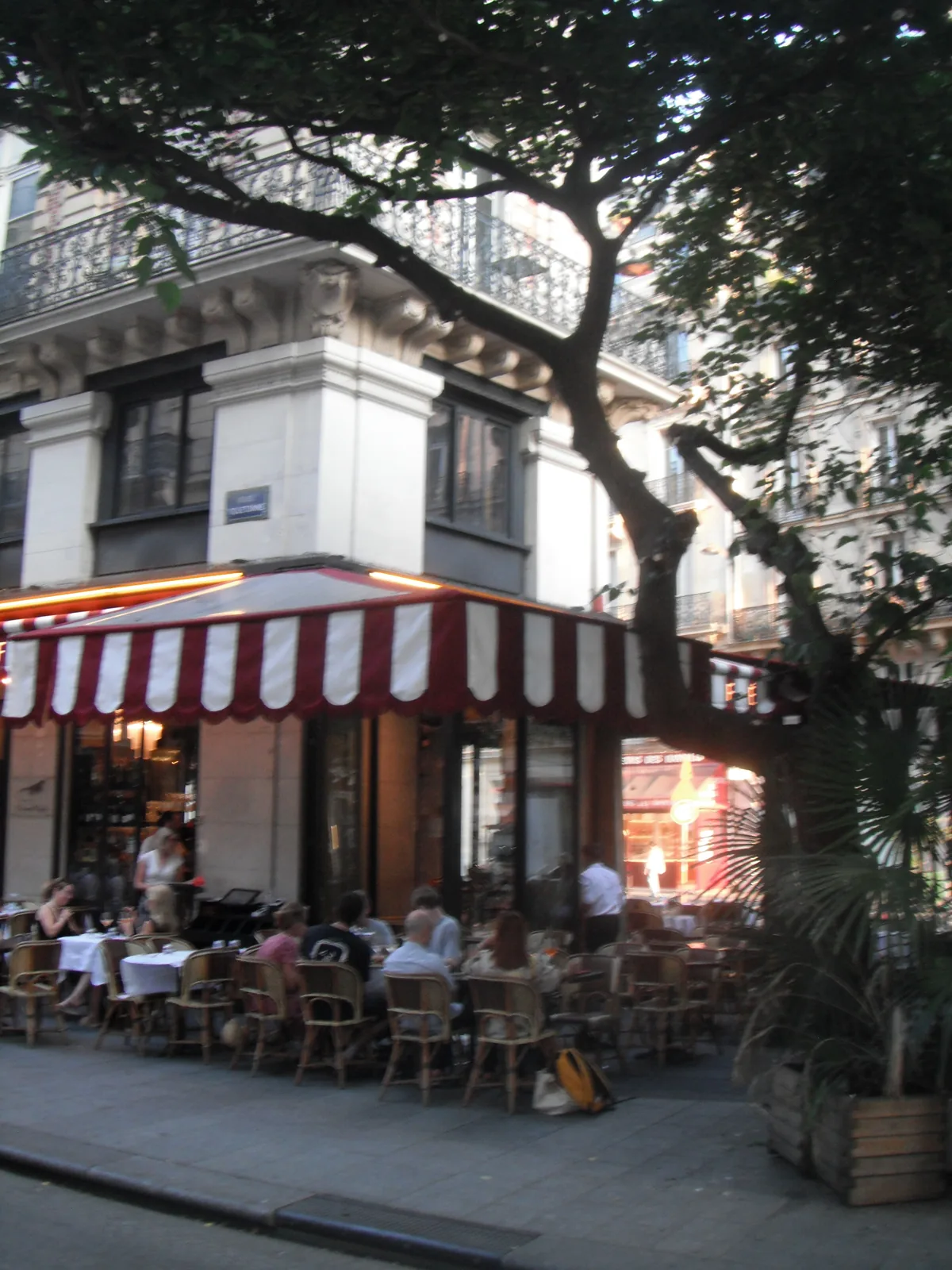 Terrasse de café sous un store rayé rouge et blanc en début de soirée, au Fujifilm FinePix XP15