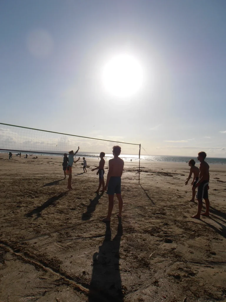 Le terrain à contre-jour, soleil bas dans le cadre et ombres allongées sur le sable