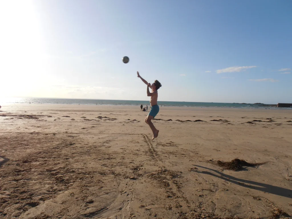 Un smash en fin de journée, l’ombre du joueur étirée sur le sable