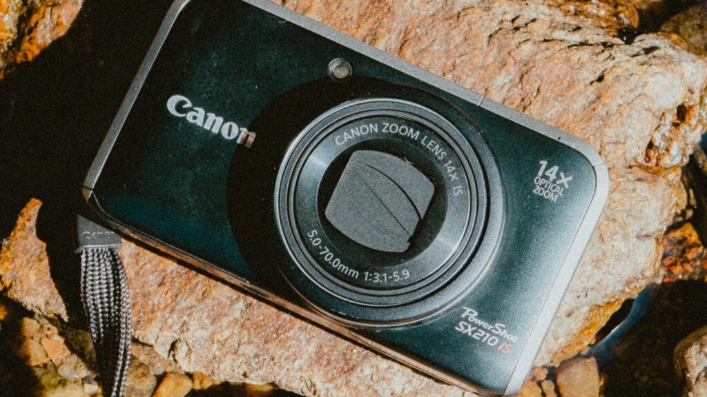 Canon PowerShot SX210 IS posé sur des galets au bord d'une rivière