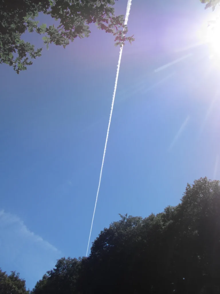Traînée d'avion et soleil dans un ciel bleu