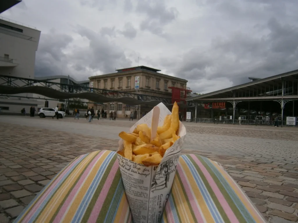 Cornet de frites sur un transat rayé face à l'entrée de la Grande Halle, photo Olympus VG-120